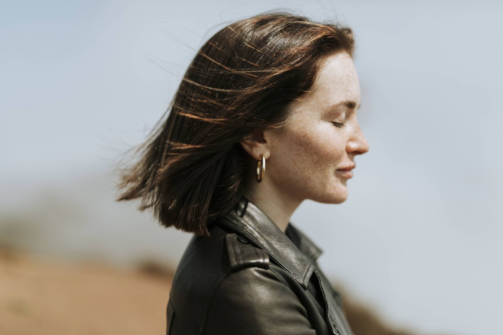 Side view of  a woman in leather jacket standing in a park